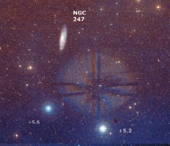 Una fotografia della regione centrata sulla galassia NGC 247; il campo inquadrato misura 2,4° nel lato lungo. Le due luminose stelle in basso sono la SAO 166585 (a sinistra) e la SAO 166528. L’alone luminoso al centro è un riflesso proveniente da Deneb Kaitos, situata quasi 3° più a nord.
