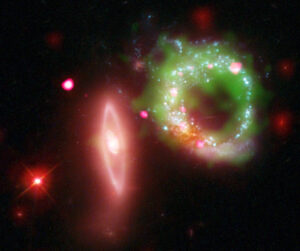 This composite image of Arp 147 shows Chandra X-ray data in pink, Hubble optical data in red, green and blue, ultraviolet GALEX data in green and infrared Spitzer data in red.