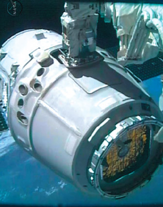 La capsula Dragon viene agganciata dal braccio robotico della ISS.